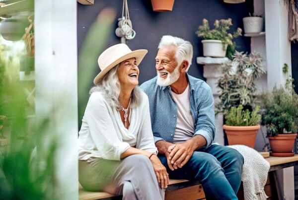 A senior couple sitting on a bench outside laughing